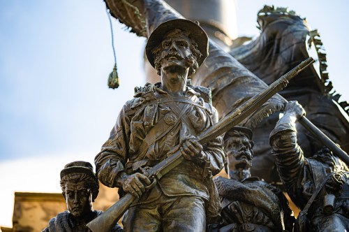 Bronze statue of a soldier holding a rifle, surrounded by other figures, depicting a historical military scene.