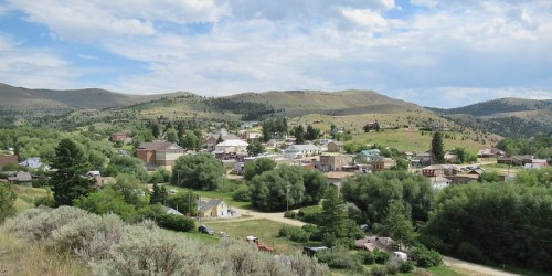 A scenic view of a small town nestled in green hills under a partly cloudy sky.