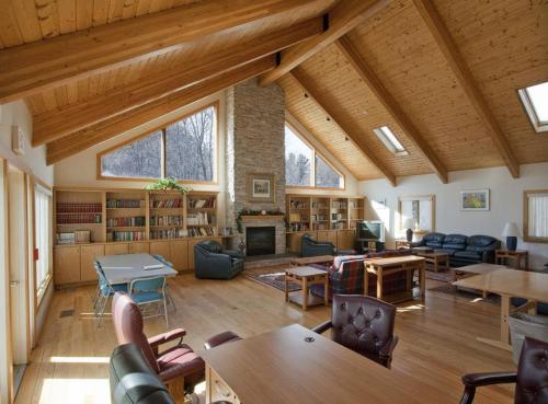 Spacious, modern living area with wooden beams, a stone fireplace, bookshelves, and comfortable seating.