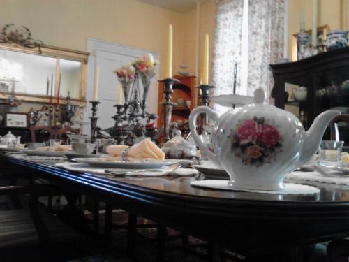 A beautifully set dining table with a floral teapot, candles, and elegant tableware in a warm, inviting room.
