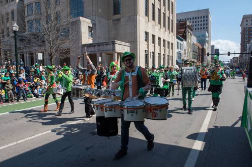 A lively St. Patrick's Day parade with musicians in green attire marching down a city street.