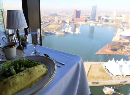 A gourmet omelet and salad on a table with a stunning view of a waterfront cityscape.