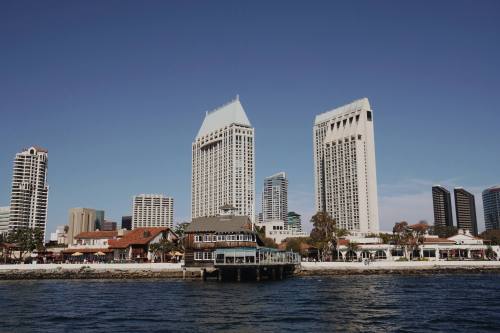 City skyline featuring modern skyscrapers and waterfront buildings under a clear blue sky.
