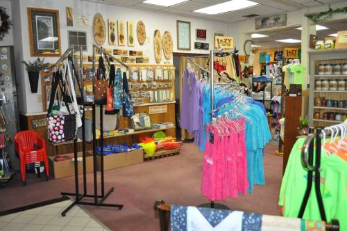 A colorful retail store interior featuring clothing racks, bags, and various merchandise displayed on shelves.