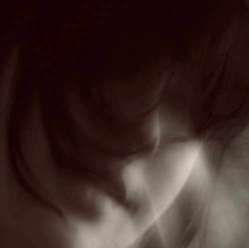 A blurred, abstract image of a person's face with soft, flowing hair, creating a dreamlike effect.