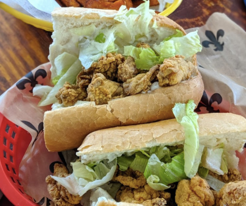 A close-up of a sandwich filled with fried chicken and lettuce, served in a red basket.