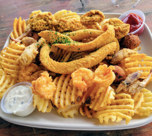 A platter of crispy fried seafood and waffle fries, served with dipping sauces.