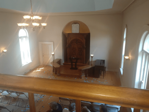 A view from above of a simple, light-filled chapel with wooden furnishings and scattered blue decorations on the floor.