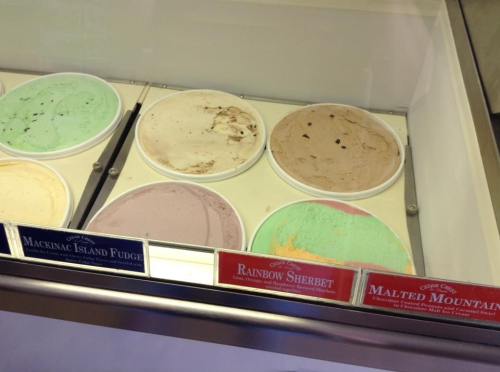 A display of ice cream tubs featuring flavors like Mackinac Island Fudge, Rainbow Sherbet, and Malted Mountain.
