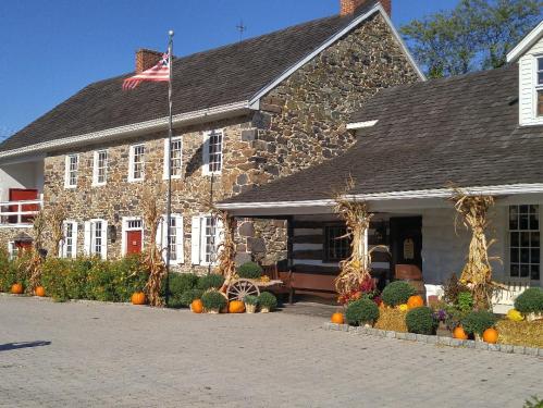 A stone building with a flag, surrounded by pumpkins and autumn decorations, set against a clear blue sky.