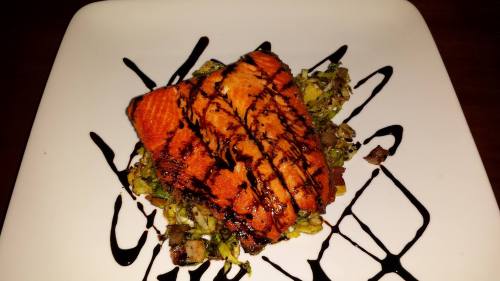 Grilled salmon fillet drizzled with balsamic glaze, served on a bed of sautéed vegetables.