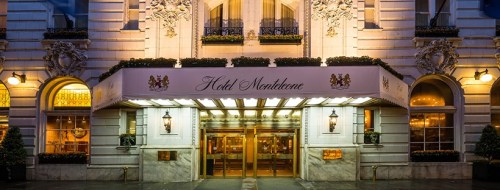 Elegant hotel entrance with a marquee, decorative architecture, and warm lighting at dusk.