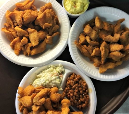 Three plates of fried food, including crispy pieces and sides of coleslaw and baked beans, on a tray.