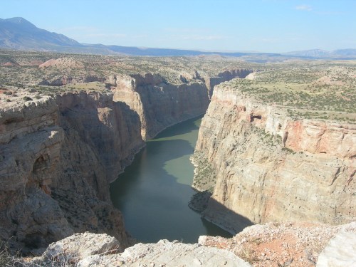A scenic view of a winding river cutting through steep canyon walls under a clear blue sky.