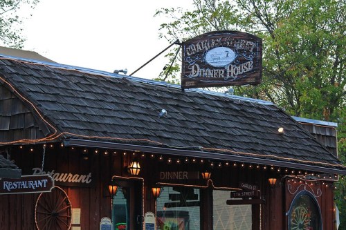 Sign for "Charlie’s Dinner House" on a rustic wooden building, with lights and trees in the background.