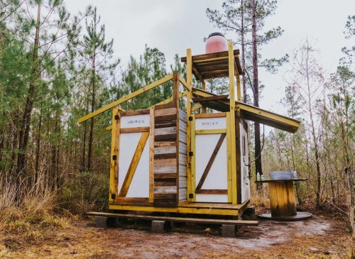 A small, colorful cabin with a wooden exterior, surrounded by trees in a natural setting.