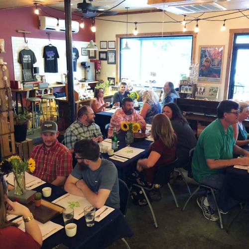 A lively restaurant scene with diners at tables, enjoying meals and conversation, surrounded by plants and decor.