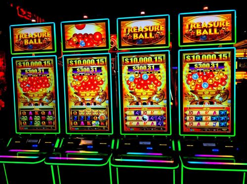 Four brightly lit slot machines displaying colorful graphics and jackpot amounts in a casino setting.