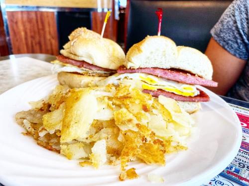 A plate with crispy hash browns and two sandwiches filled with ham and eggs, garnished with toothpicks.