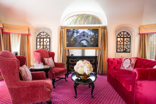 A stylish living room with pink furniture, a black coffee table, and a large TV, featuring elegant curtains and decor.