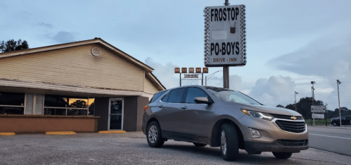 A Chevrolet Equinox parked outside a drive-in restaurant with a sign reading "Frostop Po-Boys." Cloudy sky in the background.