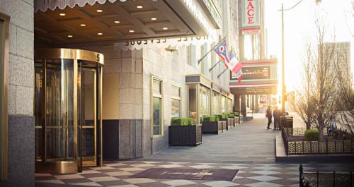 Entrance of a hotel with a revolving door, flags, and a sunset glow illuminating the sidewalk.