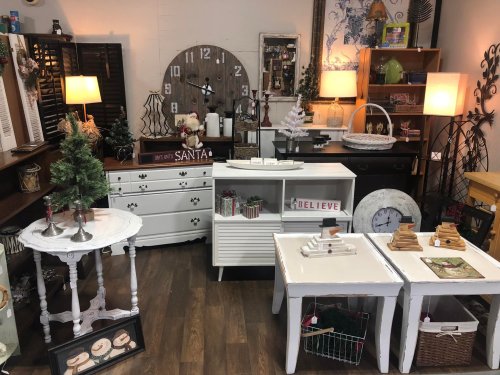 A cozy home decor display featuring various furniture pieces, holiday decorations, and small trees in a warm setting.