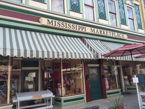 Exterior of the Mississippi Marketplace, featuring striped awnings and a decorative sign above the entrance.
