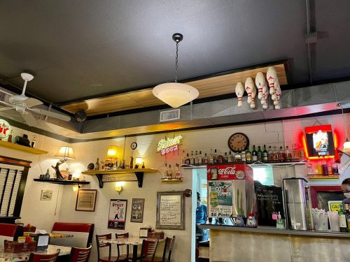 A cozy diner interior featuring retro decor, a bowling pin display, and a neon sign reading "Silver Spoon."