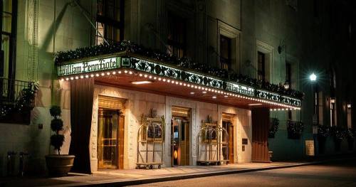 The illuminated entrance of the William Penn Hotel, adorned with festive decorations, at night.