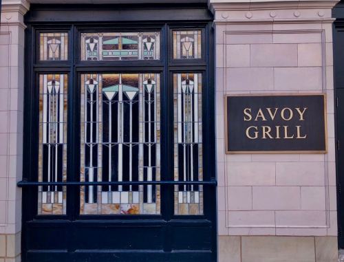 Exterior view of the Savoy Grill, featuring decorative stained glass windows and a prominent sign.