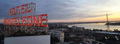 View of the Hotel Monteleone sign at sunset, overlooking a cityscape and river.