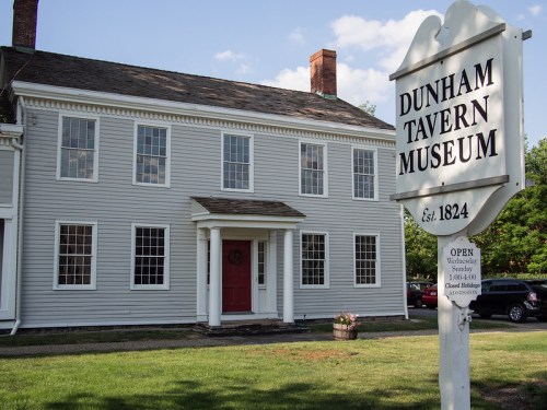 Exterior of the Dunham Tavern Museum, a historic building with a sign indicating its establishment in 1824.