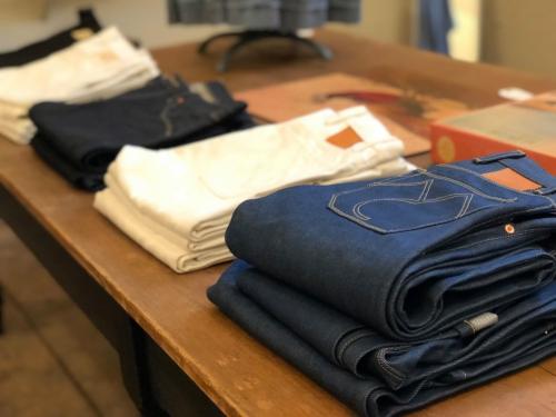 A table displaying neatly folded jeans in various colors, including dark blue, white, and black.