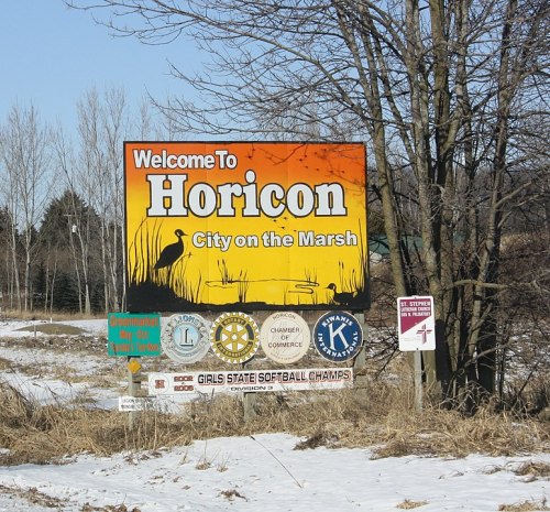 Welcome sign for Horicon, "City on the Marsh," featuring logos and a snowy landscape.