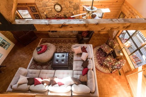 Cozy living room with a stone wall, large sofa, decorative pillows, and warm wooden accents. Bright and inviting atmosphere.