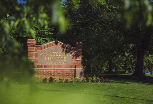 Sign for Gettysburg College, established in 1832, surrounded by greenery and flowers.