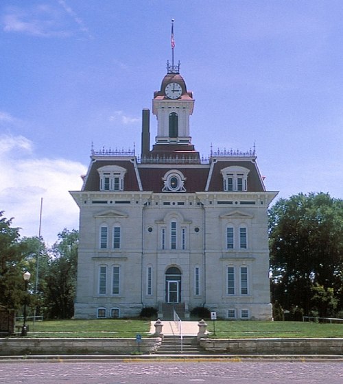 Historic courthouse with a clock tower, ornate architecture, and a grassy lawn under a clear blue sky.