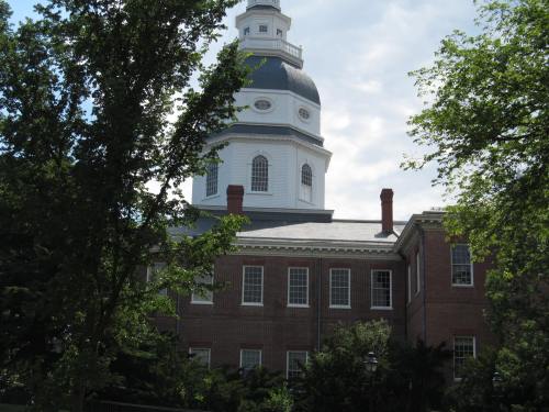Historic building with a prominent dome, surrounded by trees and a cloudy sky.