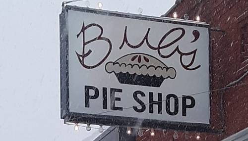 Sign for "Buli's Pie Shop" with a pie graphic, surrounded by falling snowflakes.