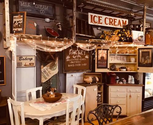 Cozy bakery interior with rustic decor, ice cream sign, and warm lighting, featuring a table and various baked goods.