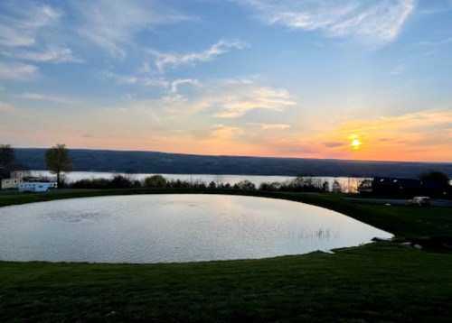 A serene sunset over a calm lake, with rolling hills and a clear sky reflecting warm colors.