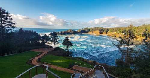 Scenic view of a coastline with waves, trees, and a grassy area under a blue sky with scattered clouds.