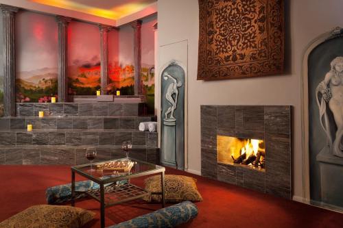 A cozy spa room with a fireplace, decorative walls, candles, and a seating area with cushions and a glass table.