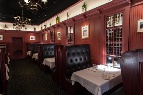 Elegant restaurant interior with dark wood booths, white tablecloths, and a wine display on the wall.