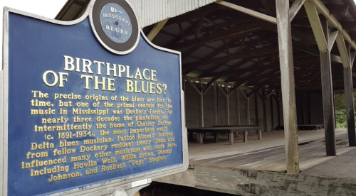 Sign reading "Birthplace of the Blues" in front of a wooden structure, highlighting the history of blues music in Mississippi.