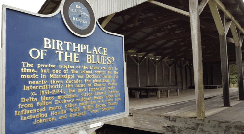 Sign reading "Birthplace of the Blues" in front of a wooden structure, highlighting the history of blues music in Mississippi.