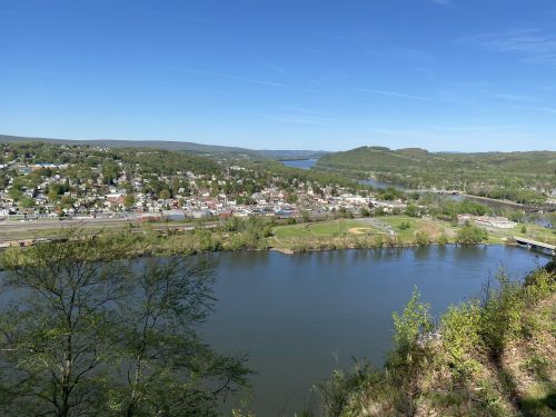 A scenic view of a river winding through a green landscape, with a small town visible in the background under a clear blue sky.