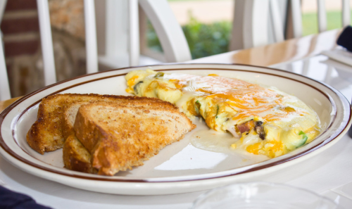 A plate with a cheesy omelette and two slices of toasted bread.