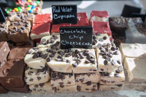 A display of assorted desserts, including red velvet cupcakes and chocolate chip cheesecake fudge, with labels.